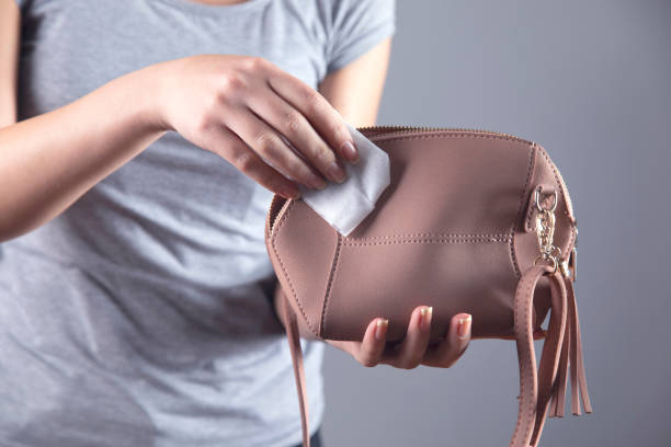 woman cleaning pink bag on grey background