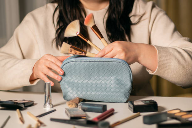 Woman putting makeup brushes in blue cosmetic bag